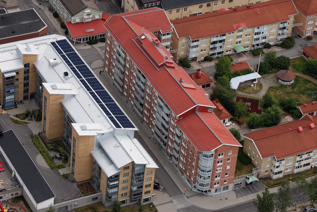Flygbild över bostadskvarter i centrala Piteå. Solpaneler syns på taket till en större fastighet längs Hamngatan.